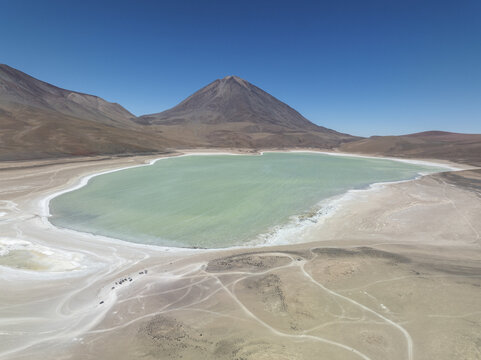 Aerial view of the striking contrast of the turquoise lake against the stark, arid landscape and towering volcano, San Pablo de L&Atilde;&shy;pez, Potosi Department, Bolivia.