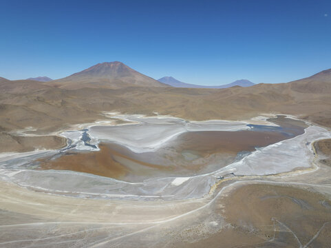 Aerial view of a stunning desert landscape with a vibrant, shallow lake reflecting the clear blue sky, framed by distant mountains, San Pablo de L&Atilde;&shy;pez, Potosi Department, Bolivia.