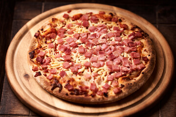Pizza with ham and mozzarella cheese on wooden background. Soft focus. Close up	