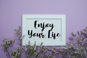 Enjoy Your Life text with flowers bouquet decoration on purple background