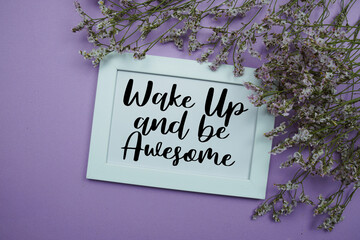 Wake Up and be Awesome text with flowers bouquet decoration on purple background