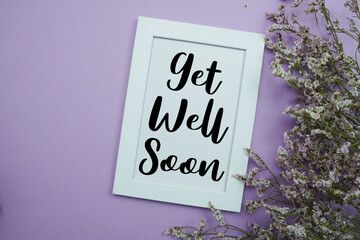 Get Well Soon text with flowers bouquet decoration on purple background