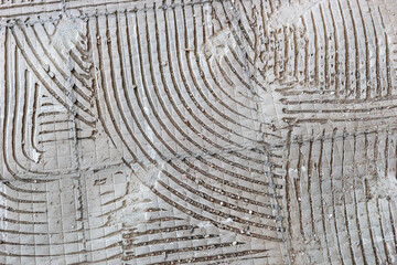 Old hard tile adhesive on the floor. Abstract pattern of notched trowel