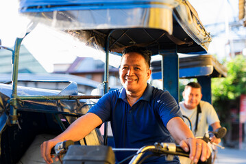 Two Filipino tricycle drivers share a joyful moment during a bright morning commute, smiling warmly at the camera while waiting on the street in Metro Manila.