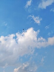 kite flying high in a clear blue sky with scattered clouds – peaceful sky view from the ground perspective