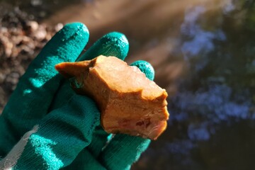 Crystalline quartz on a flint fragment in the sun, inspection of a mineral found near a river, field photo