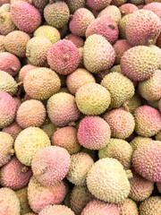 heap of  Fresh Lychee Fruits with Rough Pink-Green Skin in Natural Light on market.
