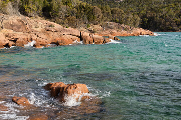 Red rocks and blue-green water in the Honeymoon Bay - Coles Bay, Tasmania, Australia