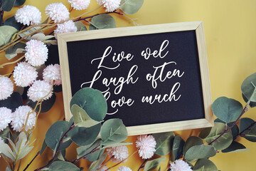 Live wel Laugh often Love muchy text with flowers decoration on yellow background