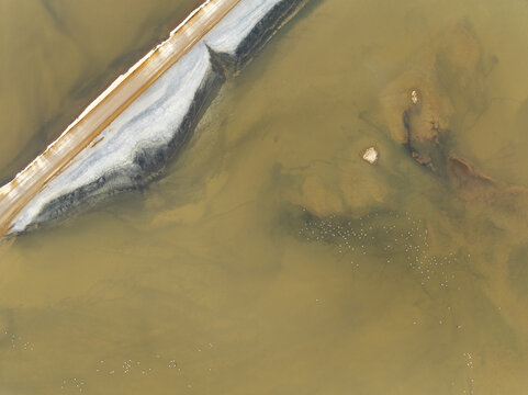 Aerial view of swirling ochre waters meeting a stark white sandy bank, creating a mesmerizing contrast of textures and tones, Windhoek, Khomas Region, Namibia.