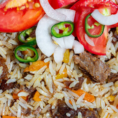 A close-up of pilaf garnished with a salad of chopped tomatoes, onions, and green chili peppers. This photo can be used in any food-themed design