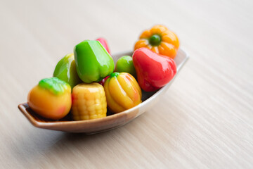 Thai Luk Chup, a traditional Thai mung bean sweet, dessert in vibrant colors shaped like miniature fruits, beautifully arranged on a small plate with soft natural lighting.