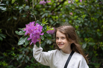 Child exploring a rhododendron flower with her hand. Concept: sensory curiosity, childhood...
