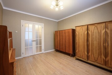room featuring hardwood floors, light walls, and white trim. Two wooden wardrobes and a set of...
