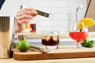 Mixologist preparing alcoholic drink in the glass at home. Female bartender hand making cocktail....