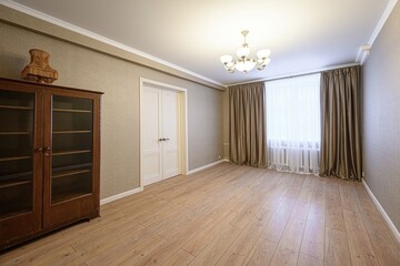 well-lit, empty room features wood floors, a large wooden cabinet, white double doors, and brown...