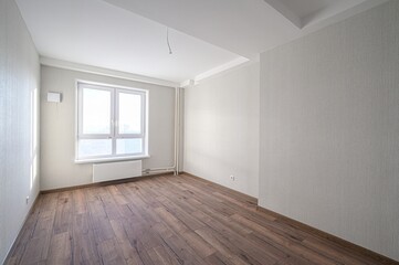bright, empty room with wood floors, white walls, and a window. The space feels clean and modern