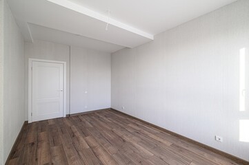 bright, empty room with wood floors, light walls, and a white door