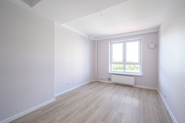 Bright, empty room with light wood floors, soft-toned walls, and a large window. Clean, minimalist...
