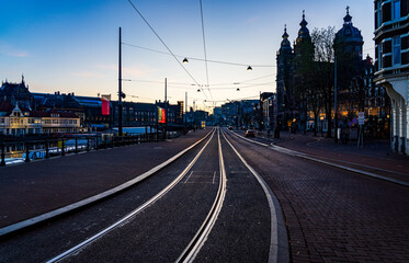An atmospheric dawn view of Amsterdam, with leading lines from tram tracks creating a path through the awakening historic city center