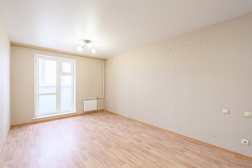 Empty room with wood flooring, beige walls, a white ceiling, and a window with a radiator underneath. A simple ceiling light fixture is present