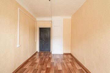 empty room with yellow walls, wood flooring, a black door, and a white closet. Bare bulb