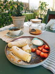 Morning breakfast on a cafe terrace.Sweet breakfast table setting. A plate with rolled crepes...