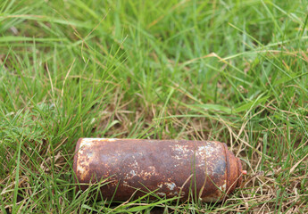 An old rusty can lay on the grass.