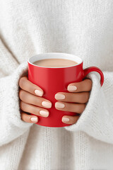A woman is holding a red coffee cup