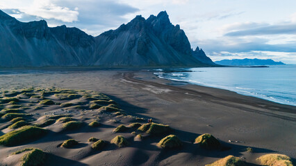 Dramatic peaks of Vestrahorn tower over the tranquil waters at Stokksnes Beach in Iceland,...