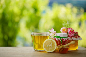 Honey in a glass jar and lemon with green background