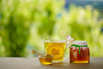 Honey in a glass jar and lemon with green background