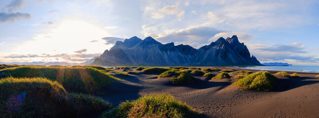 Vestrahorn mountain towers imposingly over Stokksnes beach, framed by soft grasses against the dark...