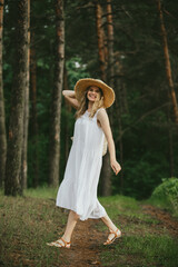 Tourist walking in forest wearing white dress and straw hat
