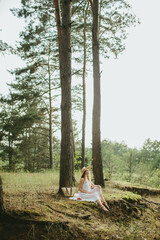 Young woman wearing white dress and straw hat relaxing in forest