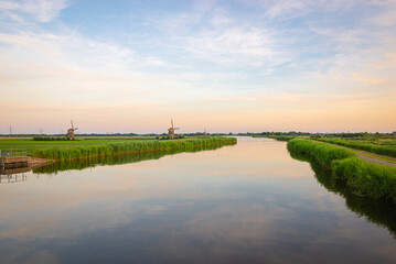 Wide view of the calm water of river Rotte, western Netherlands with windmills in the distance.