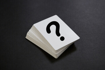 Stack of playing cards, printed with a question mark on dark background