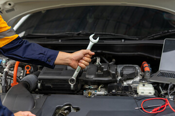 Mechanic holding wrench near car engine, ready for repair
