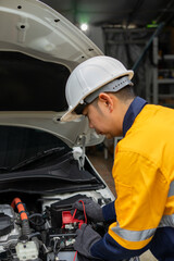 Mechanic in hard hat and gloves works on car engine