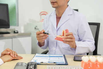 Dentist explaining dental care with model in clinic office