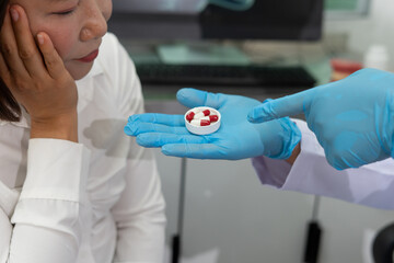 Doctor in blue gloves shows red and white capsules to concerned patient