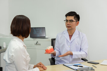 Dentist explains dental care to patient using model