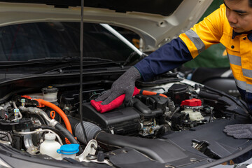 Mechanic cleaning car engine with red cloth, wearing safety gloves