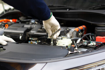 Mechanic working on car engine with tools, wearing gloves for safety