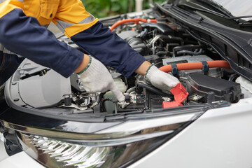 Mechanic inspecting car engine with focus on battery and cables