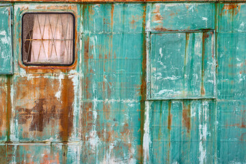 Rusty green metal wall with window and door in industrial setting
