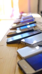 Row of various smartphones on a light wooden table