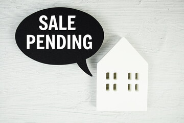 Sale Pending text message with white house model on concrete background