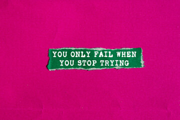 You Only Fail When You Stop Trying message written on ripped torn green paper piece on pink...