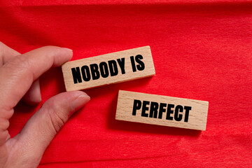 Nobody is Perfect message written on wooden blocks on red background. Conceptual Nobody is Perfect...